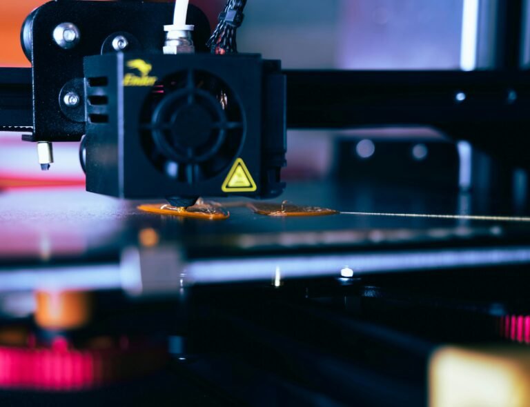 Close-up of a 3D printer nozzle extruding molten filament onto the build plate, showcasing the printing process with a focus on the printer's components and precision technology.